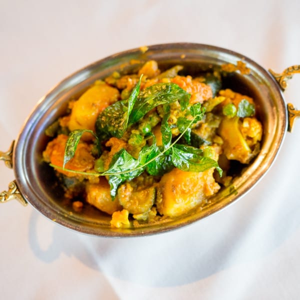 Maharaja Indian Restaurant's mixed vegetable curry in a traditional silver serving dish with gold handles.