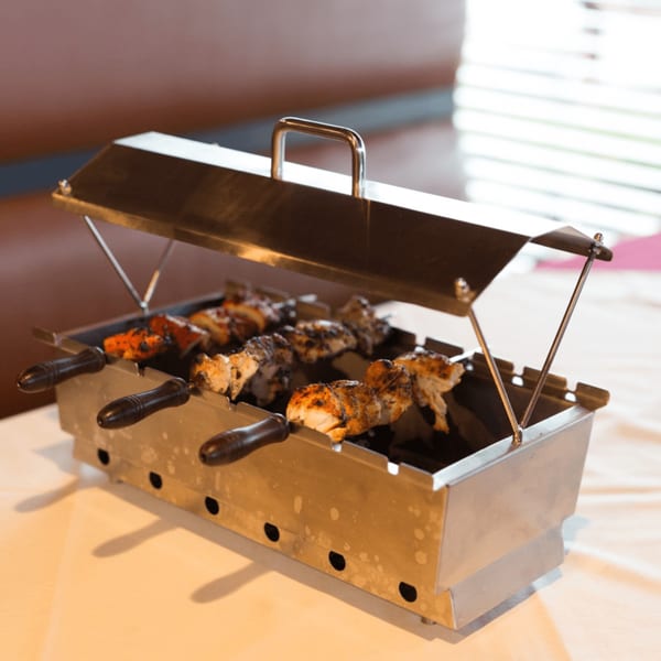 Maharaja Indian Restaurant's grilled chicken and paneer skewers cooking in a tabletop tandoor.