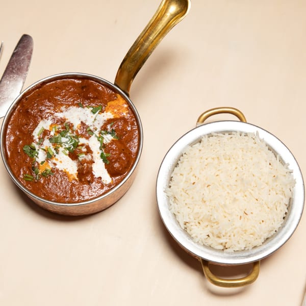 Maharaja Indian Restaurant's butter chicken, garnished with cream and cilantro, served with white rice.