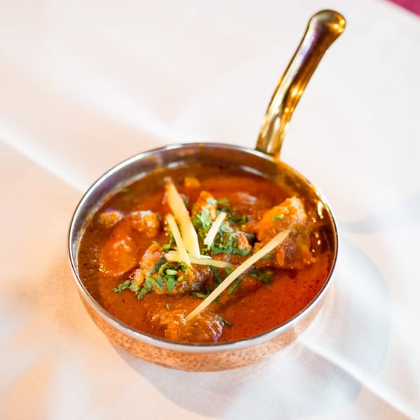 Maharaja Indian Restaurant's chicken curry, garnished with ginger and cilantro, in a copper karahi.