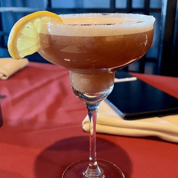A Maharaja Indian Restaurant cocktail with a lemon slice and sugar rim on a red tablecloth.